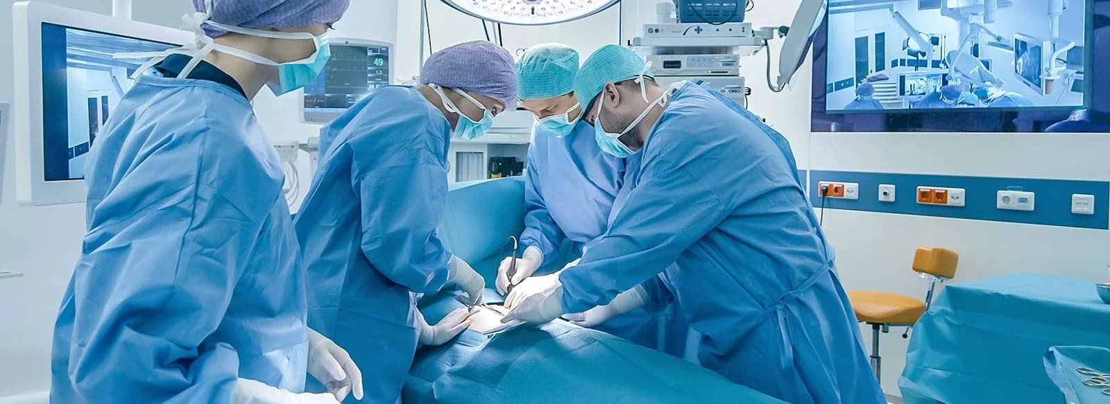 Surgical team wearing gowns and working with surgical drapes